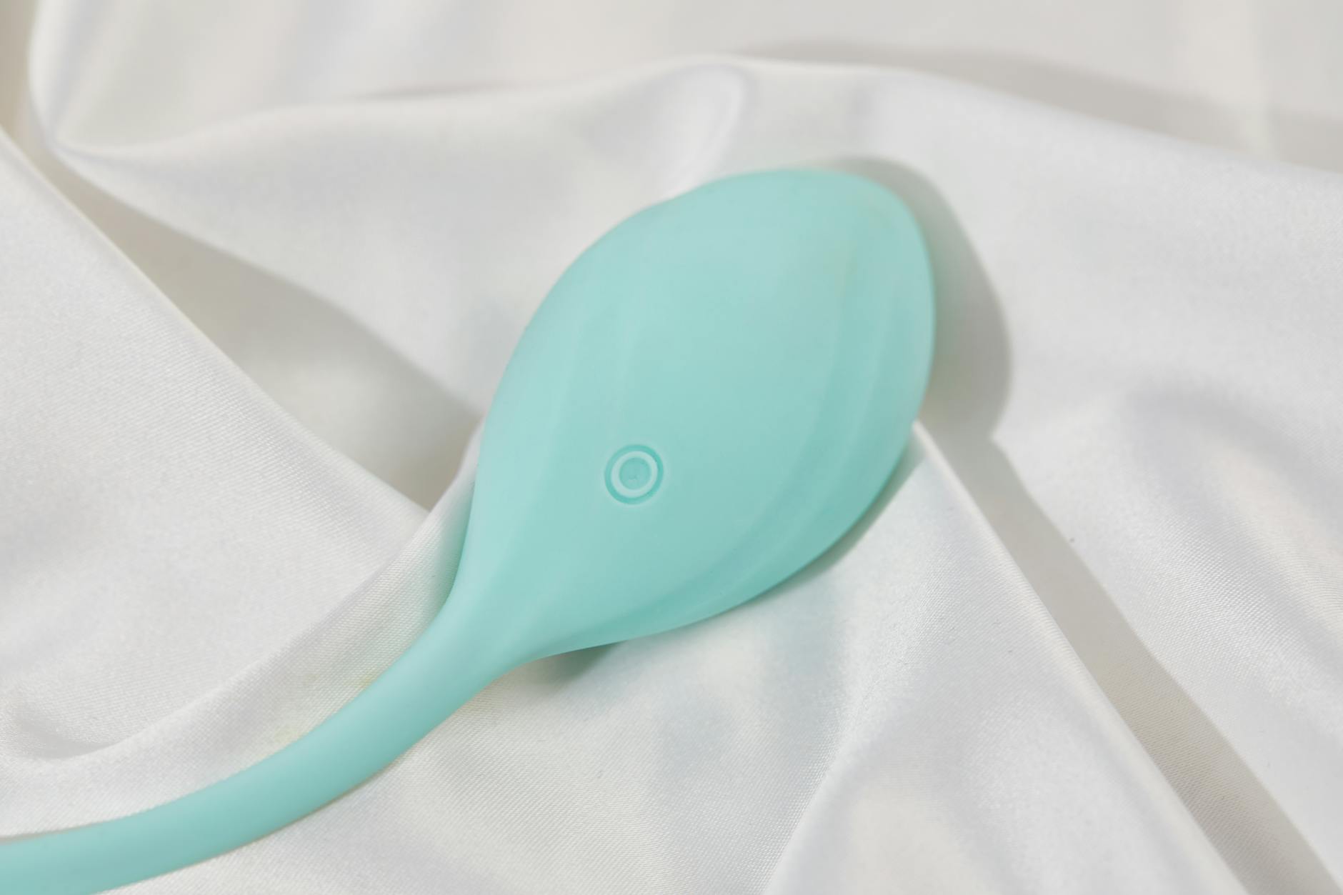 Vibrador amarelo vibrante em fundo de tecido de seda branco, mostrando design liso e moderno