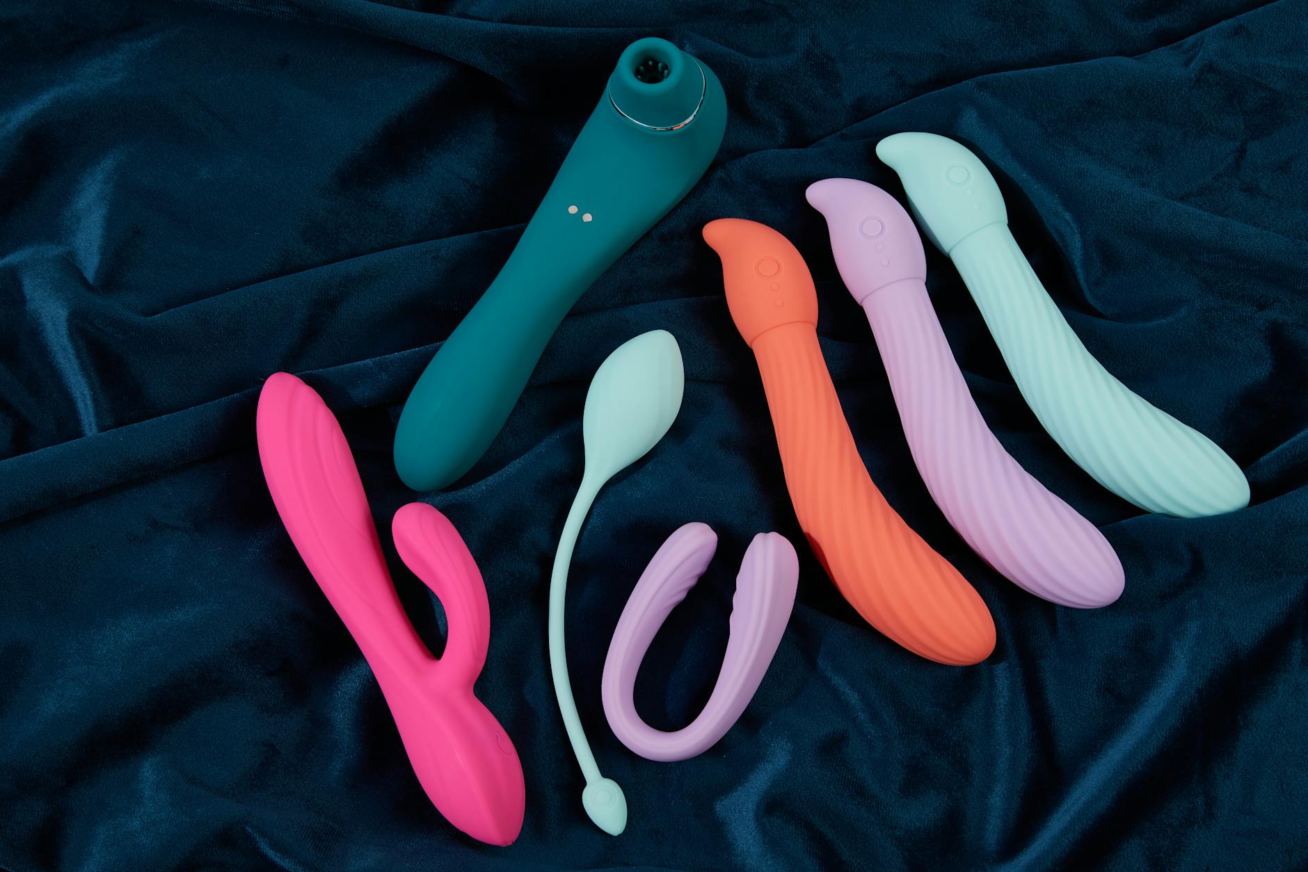 Mão segurando um vibrador de cor vibrante contra fundo roxo minimalista
