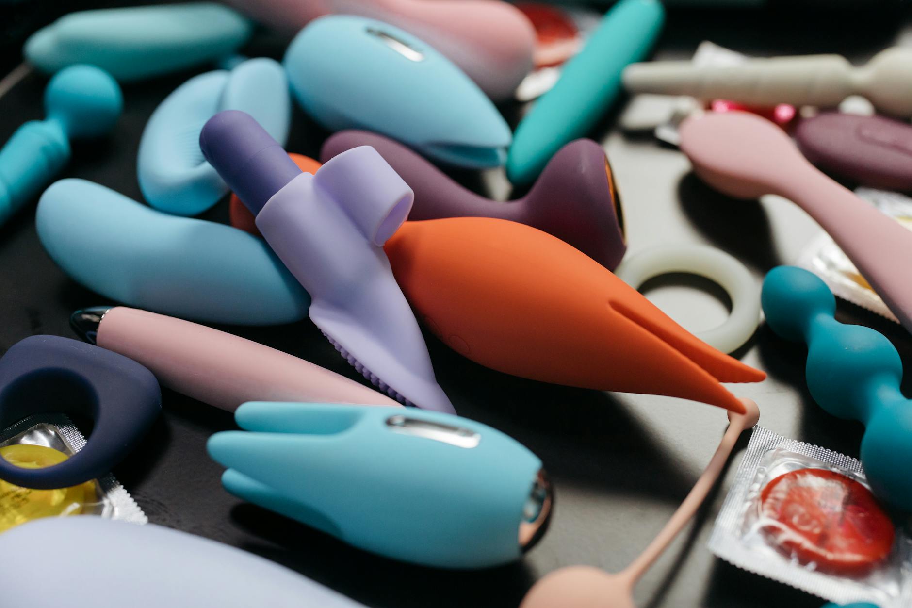 Mulher segurando vibradores de silicone em tons de azul e rosa, expressão contemplativa