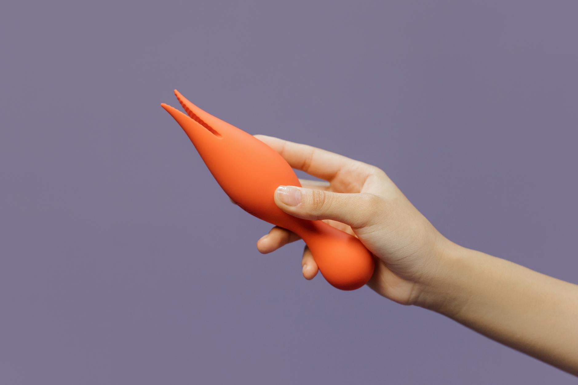 Mão segurando um vibrador de cor vibrante contra um fundo minimalista, simbolizando confiança e prazer pessoal.