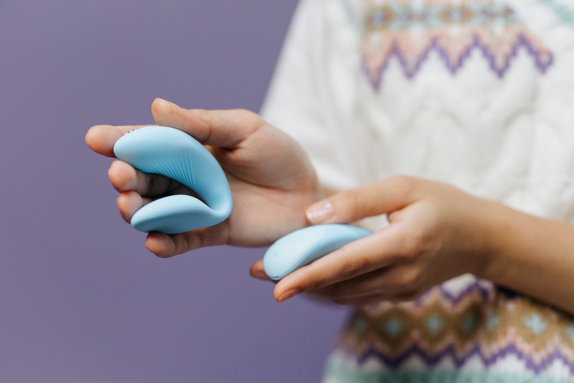A hand holding a sleek blue vibrator, symbolizing control and safety in pleasure