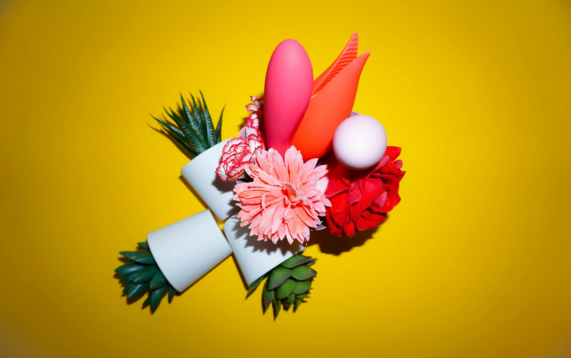 Arranjo colorido de flores e objetos abstratos em fundo amarelo brilhante, simbolizando prazer renovado