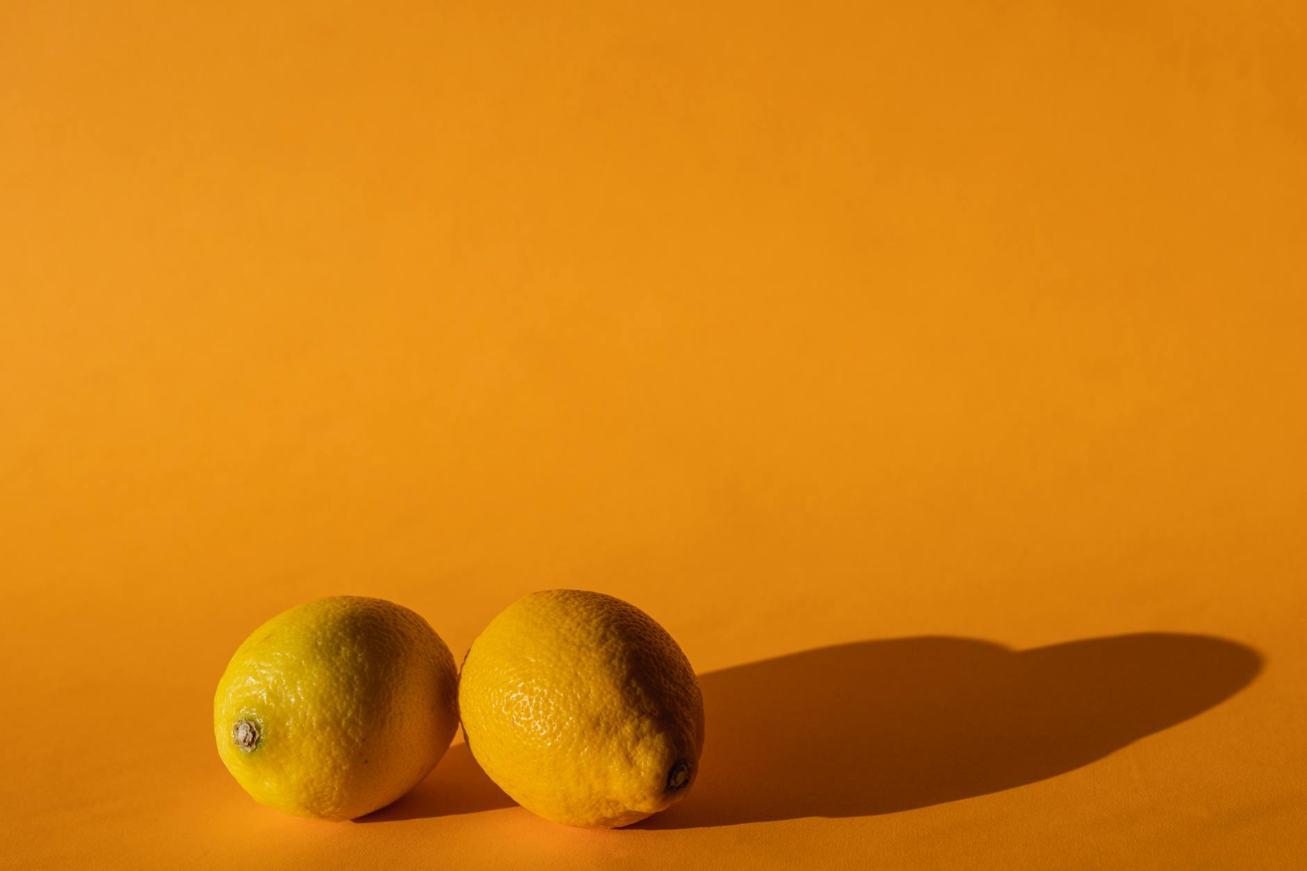 Vibrador amarelo de silicone ao lado de frutas em fundo amarelo, representando prazer e bem-estar sensual